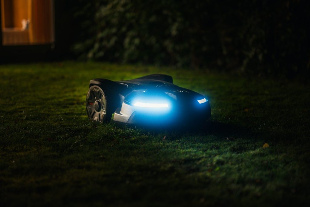Robot tondeuse éclairé en fonctionnement sur une pelouse