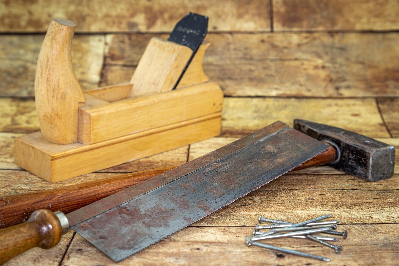 Outils de bricolage (hache, marteau, clous) posés sur du bois
