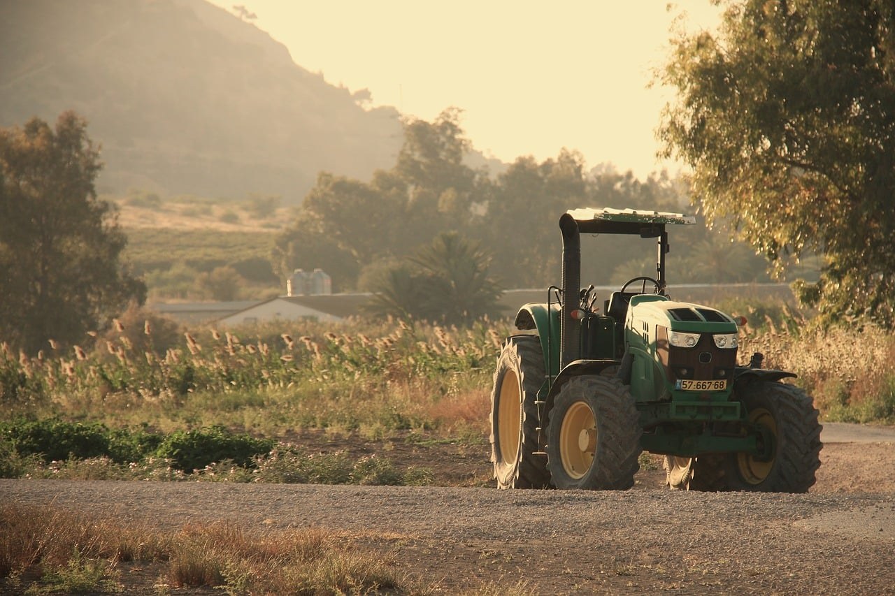 Tracteur vert au travail dans un champ, illustrant le travail des agriculteurs français