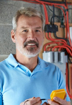 Électricien artisan en polo bleu travaillant sur un tableau électrique