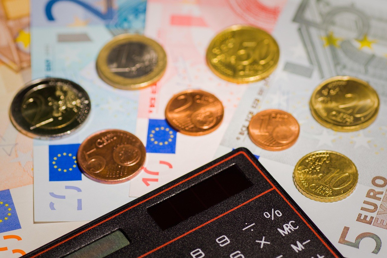 Pièces et billets en euros avec une calculatrice, symbole du budget ménage face aux factures