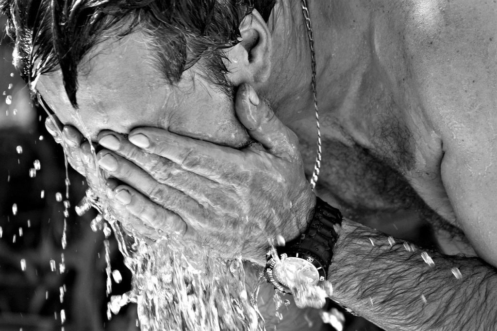Personne se rafraichissant le visage avec de l'eau en periode de forte chaleur